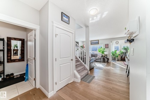 This inviting entryway features light hardwood flooring, a white staircase with carpeted treads, and a convenient closet with a tiled floor - 22407 99 Avenue, Edmonton, AB - Indoor Photo Showing Other Room