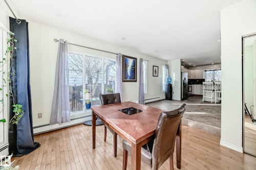Dining area featuring hardwood floors, large windows with natural light, and a view into the kitchen area - 16232 100 Street, Edmonton, AB - Indoor