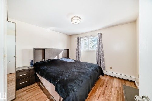 This room features hardwood flooring, a window with patterned curtains, and a ceiling light fixture - 16232 100 Street, Edmonton, AB - Indoor Photo Showing Bedroom