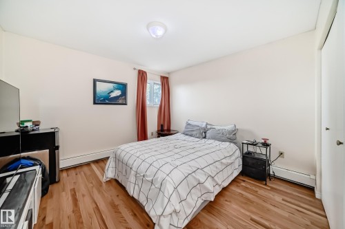 This room features hardwood floors, a window with red curtains, and a ceiling light fixture - 16232 100 Street, Edmonton, AB - Indoor Photo Showing Bedroom