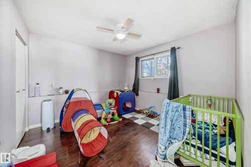 This room features hardwood flooring, light purple walls, and a window with dark curtains - 16232 100 Street, Edmonton, AB - Indoor