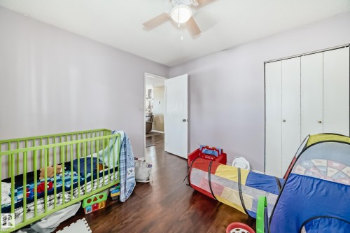 This room features wood flooring, a ceiling fan with integrated lighting, and white bi-fold closet doors - 16232 100 Street, Edmonton, AB - Indoor Photo Showing Bedroom