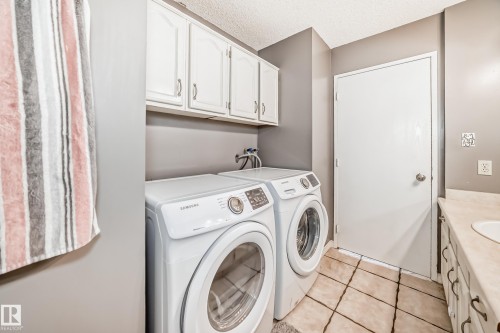 Utility area featuring a washer and dryer, white cabinetry, and a countertop with a sink - 16232 100 Street, Edmonton, AB - Indoor Photo Showing Laundry Room