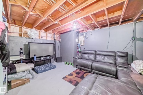 This spacious room features an exposed beam ceiling, painted walls, and a light-colored floor - 16232 100 Street, Edmonton, AB - Indoor