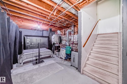 Utility room with exposed wooden ceiling joists, grey painted walls, and a carpeted staircase with a wooden handrail - 16232 100 Street, Edmonton, AB - Indoor