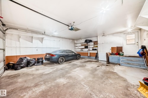 The property includes a spacious garage with a concrete floor, integrated shelving for storage, and a pedestrian door for entry and exit - 16232 100 Street, Edmonton, AB - Indoor Photo Showing Garage