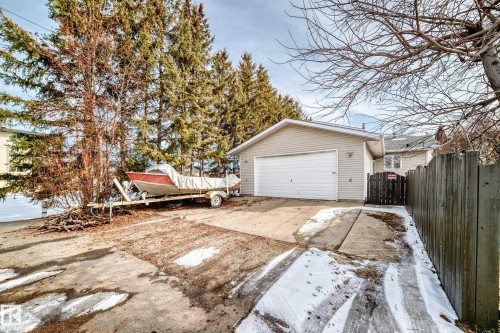 The property features a private driveway leading to an attached garage with a white door, and a wooden fence on one side - 16232 100 Street, Edmonton, AB - Outdoor