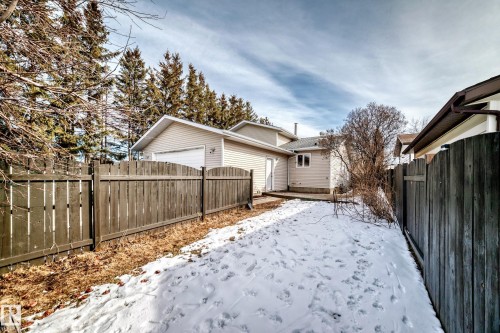 The property features a fenced yard with a combination of wooden and evergreen trees, a detached garage, and an exterior patio area - 16232 100 Street, Edmonton, AB - Outdoor