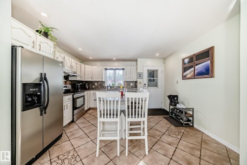 The kitchen features white cabinetry, stainless steel appliances, and a tiled floor - 16232 100 Street, Edmonton, AB - Indoor Photo Showing Kitchen