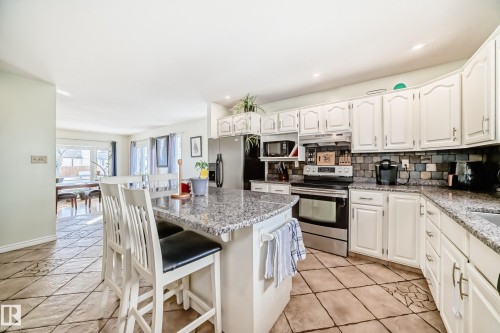 The kitchen features granite countertops, a tiled backsplash, and white cabinetry - 16232 100 Street, Edmonton, AB - Indoor Photo Showing Kitchen