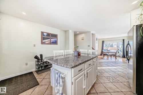 The kitchen features a functional island with a granite-style countertop and cabinetry, along with tile flooring - 16232 100 Street, Edmonton, AB - Indoor