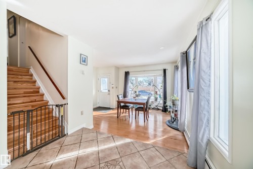 The property features a staircase with wood treads and a wood handrail, a tiled entryway, and hardwood flooring in the living area - 16232 100 Street, Edmonton, AB - Indoor