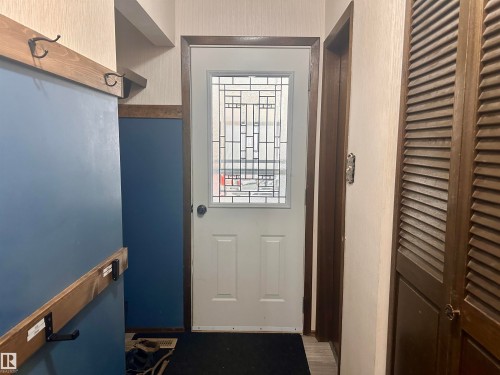 Entryway featuring a white door with decorative glass, and contrasting blue and cream walls - 9915 95 Street, Westlock, AB - Indoor Photo Showing Other Room