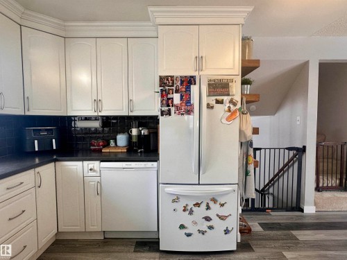 Kitchen featuring white cabinetry, dark countertops, and a black tiled backsplash - 9915 95 Street, Westlock, AB - Indoor Photo Showing Kitchen