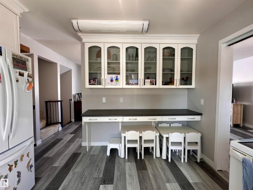 The property features modern plank flooring, white upper cabinetry with glass inserts, and a built-in counter space - 9915 95 Street, Westlock, AB - Indoor
