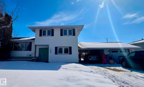 The property features a white exterior with black window shutters, a front lawn, and an attached carport - 9915 95 Street, Westlock, AB - Outdoor With Facade