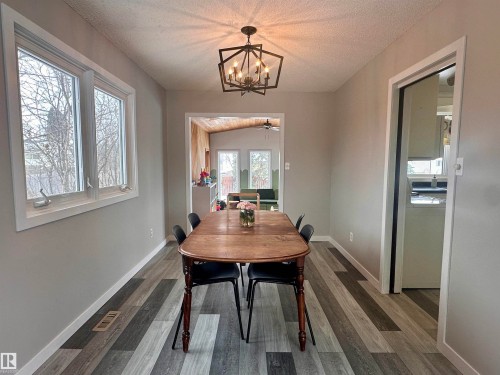Dining area featuring plank-style flooring, light-colored walls, and a contemporary light fixture - 9915 95 Street, Westlock, AB - Indoor Photo Showing Dining Room