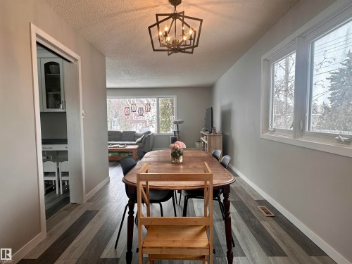 The property features a dining area with a wood-top table and dark chairs, wood-style flooring, a decorative light fixture, and windows providing natural light - 9915 95 Street, Westlock, AB - Indoor Photo Showing Dining Room