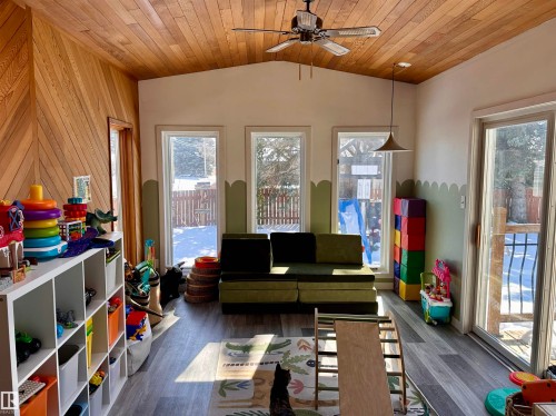 This bright room features a wooden vaulted ceiling, a ceiling fan, and large windows offering views of the outdoors - 9915 95 Street, Westlock, AB - Indoor Photo Showing Other Room