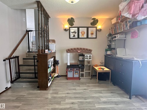 The property features a staircase with a wooden railing and a light-colored flooring - 9915 95 Street, Westlock, AB - Indoor Photo Showing Other Room