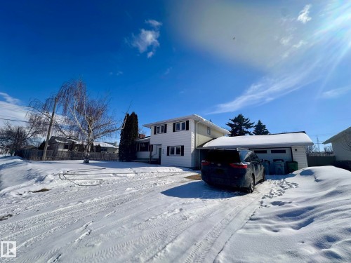 The property features a white two-story exterior with dark window shutters, an attached garage, and a driveway - 9915 95 Street, Westlock, AB - Outdoor