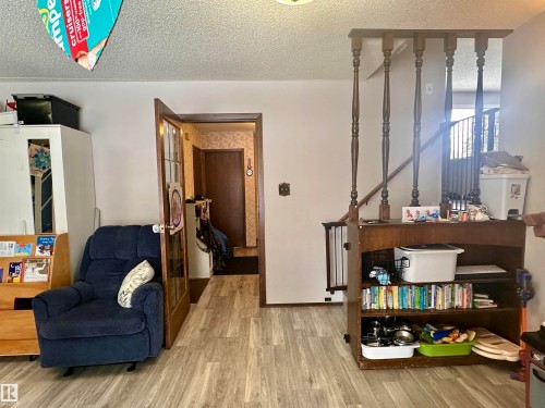 The interior features light-toned flooring, white walls, and a wooden staircase with decorative balusters - 9915 95 Street, Westlock, AB - Indoor