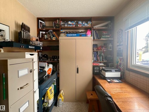 This room features a window with blinds, a built-in desk, and extensive shelving - 9915 95 Street, Westlock, AB - Indoor