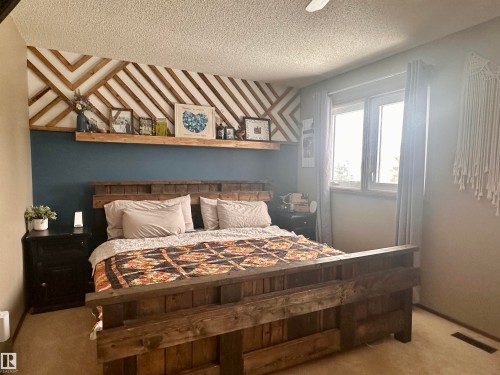 The bedroom features a decorative wall accent, a window providing natural light, and carpeted flooring - 9915 95 Street, Westlock, AB - Indoor Photo Showing Bedroom