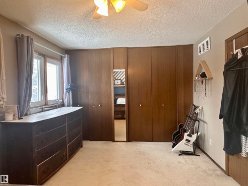 This space features neutral-toned carpeting, a window with natural light, and paneled walls with integrated closet doors - 9915 95 Street, Westlock, AB - Indoor