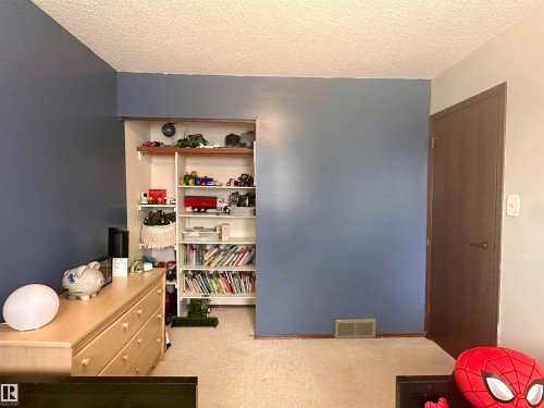 This room features light-colored carpeting, blue painted walls, and a recessed shelving unit - 9915 95 Street, Westlock, AB - Indoor