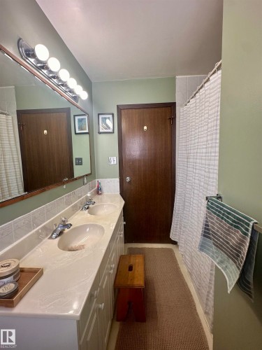 Bathroom featuring a double vanity with integrated sinks, a mirror, and a shower with a shower curtain - 9915 95 Street, Westlock, AB - Indoor Photo Showing Bathroom