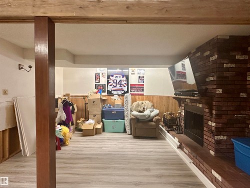 The property features a spacious room with light-colored flooring and wood paneling on the lower walls - 9915 95 Street, Westlock, AB - Indoor Photo Showing Other Room With Fireplace