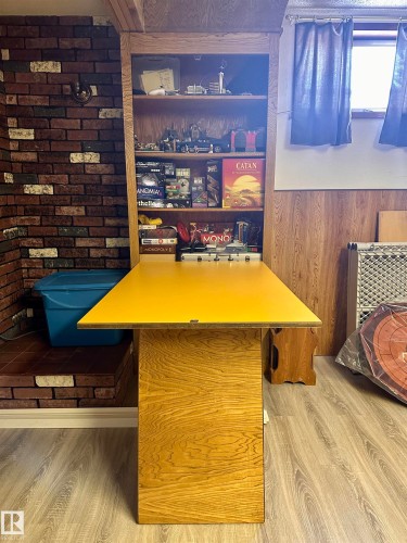 This room features wood-look flooring, a partial brick wall, and a window with curtains - 9915 95 Street, Westlock, AB - Indoor