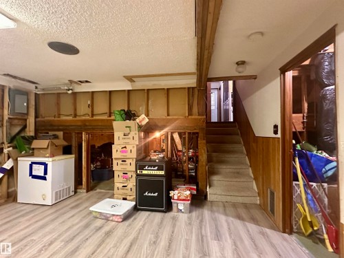 The lower level features laminate wood-style flooring and a carpeted staircase - 9915 95 Street, Westlock, AB - Indoor Photo Showing Other Room
