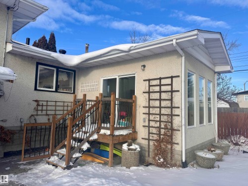 Exterior view of the property featuring stucco siding, multiple windows, a deck with wooden railings, and a sunroom - 9915 95 Street, Westlock, AB - Outdoor