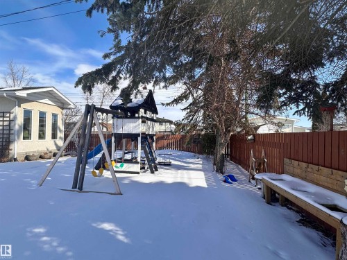 The property features a fenced yard with mature trees and a play structure - 9915 95 Street, Westlock, AB - Outdoor