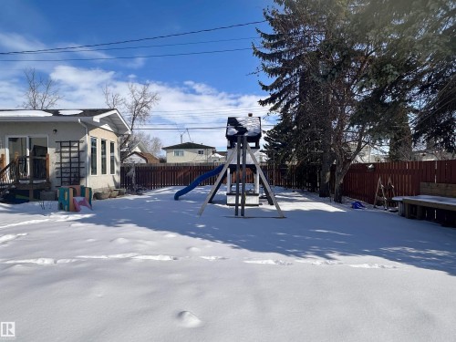 The property features a fenced yard with mature trees and a deck - 9915 95 Street, Westlock, AB - Outdoor