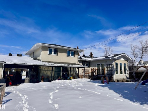 The property features a stucco exterior, a dark roof, and a carport - 9915 95 Street, Westlock, AB - Outdoor