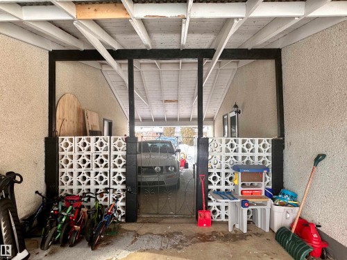 The property features a covered carport with exposed white ceiling beams, textured exterior walls, and decorative white breeze block accents - 9915 95 Street, Westlock, AB - Indoor