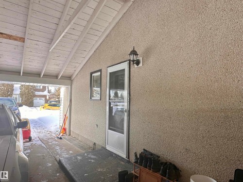 The property features an exterior wall with textured stucco finish, an outdoor light fixture, and a white screen door - 9915 95 Street, Westlock, AB - Outdoor