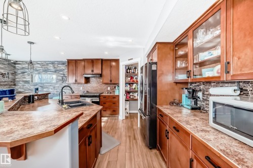 The kitchen features wood cabinetry, a central island with a sink, and countertops with a unique pattern - 6303 2 Avenue, Edmonton, AB - Indoor Photo Showing Kitchen With Double Sink