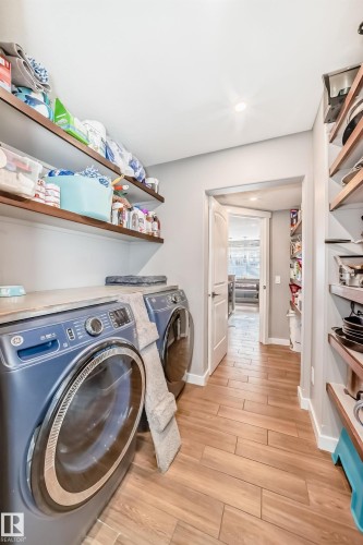 Laundry area with a washer and dryer, hardwood style flooring, and open shelving - 6303 2 Avenue, Edmonton, AB - Indoor Photo Showing Laundry Room