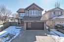 This property features a two-story exterior with light gray siding and dark gray trim, complemented by stone accents on the facade and around the garage - 6303 2 Avenue, Edmonton, AB  - Outdoor With Facade 