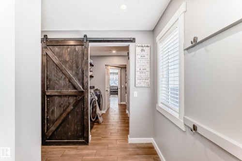 Functional space featuring a dark wood barn door, light grey walls, and wood-look tile flooring - 6303 2 Avenue, Edmonton, AB - Indoor Photo Showing Other Room