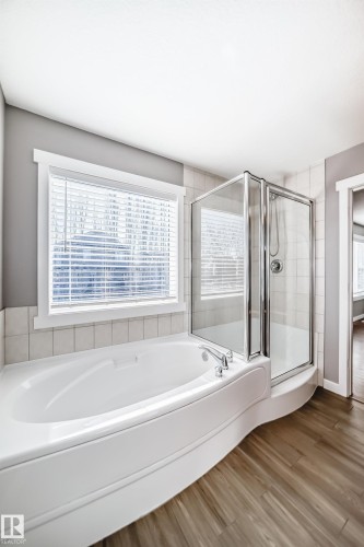 Bathroom featuring a built-in bathtub, a glass-enclosed shower, and wood-look flooring - 6303 2 Avenue, Edmonton, AB - Indoor Photo Showing Bathroom