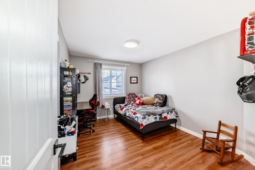 This room features wood flooring, light grey walls, and a window with white blinds and grey curtains - 6303 2 Avenue, Edmonton, AB - Indoor Photo Showing Bedroom