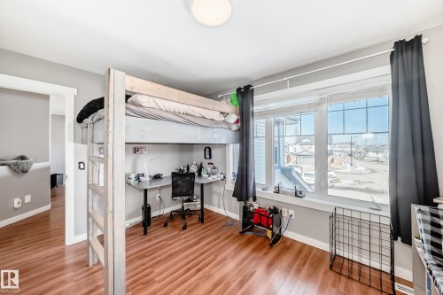 This room features warm-toned flooring and a large window with white framing, allowing for ample natural light - 6303 2 Avenue, Edmonton, AB - Indoor