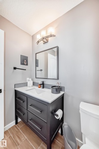 Bathroom featuring a dark wood vanity with a white countertop and a rectangular sink, complemented by a wall-mounted mirror - 6303 2 Avenue, Edmonton, AB - Indoor Photo Showing Bathroom