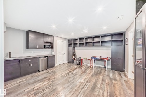 This versatile room features extensive built-in shelving, durable wood-look flooring, and recessed ceiling lighting - 6303 2 Avenue, Edmonton, AB - Indoor