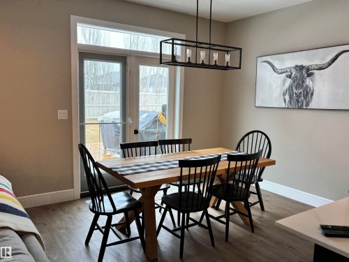 Dining area featuring light wood flooring, a modern linear chandelier, and French doors leading to the outdoors - 137 Graybriar Drive, Stony Plain, AB - Indoor Photo Showing Dining Room